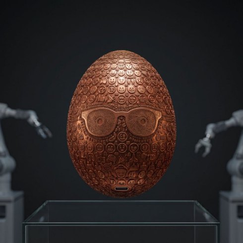 A copper egg levitating over a glass vitrine with robot arms behind it.